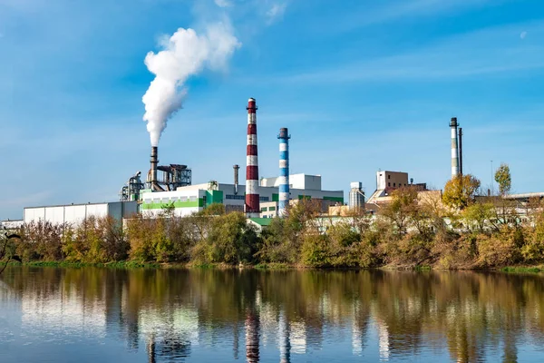 Nehir kenarındaki kereste fabrikası boruları. Hava kirliliği konsepti. Endüstriyel arazi çevresel kirlilik termik enerji santralinin atıkları