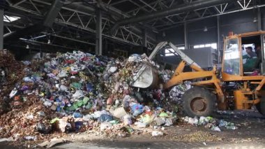 Grodno, Belarus - Ekim 2019: kazıcı modern atık geri dönüşüm tesisinde çöp yığını oluşturuyor. Çöp toplama ve ayıklama. Atıkların geri dönüşümü ve depolanması