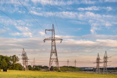 Güzel akşam bulutlarının arkasındaki yüksek voltajlı elektrik kulelerinin silueti.