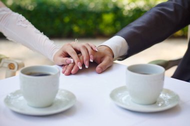 Damat gelini düğün buketiyle kucaklıyor. Yeni evli bir çiftin elindeki yüzükler. Gelin ellerini damadın omuzlarına koydu.. 