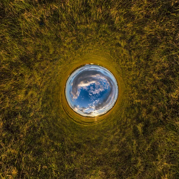 Inversion of little planet transformation of spherical panorama 360 degrees. Spherical abstract aerial view on field with awesome beautiful clouds. Curvature of space.