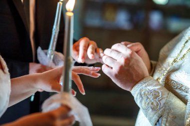 Rahip, kilisedeki nikah töreninde yeni evlilere yüzüklerini takmalarında yardımcı olur.