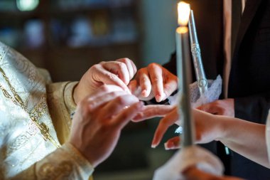 Rahip, kilisedeki nikah töreninde yeni evlilere yüzüklerini takmalarında yardımcı olur.