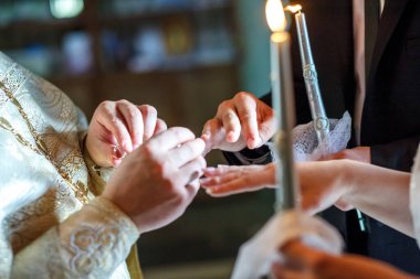 Rahip, kilisedeki nikah töreninde yeni evlilere yüzüklerini takmalarında yardımcı olur.