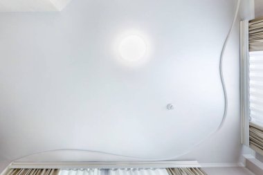 Halojen lambalı asma tavan ve boş bir oda ya da evde alçıpan inşaatı. Gergin tavan beyaz ve karmaşık şekil.