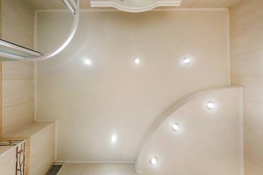 Halojen lambalı asma tavan ve boş bir oda ya da evde alçıpan inşaatı. Gergin tavan beyaz ve karmaşık şekil.