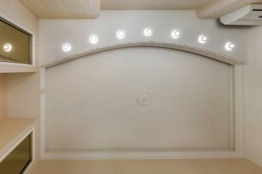 Halojen lambalı asma tavan ve boş bir oda ya da evde alçıpan inşaatı. Gergin tavan beyaz ve karmaşık şekil.