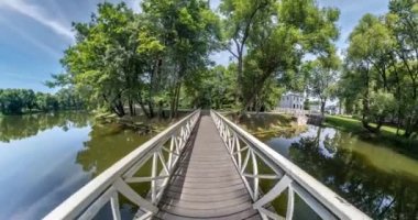 Uzay eğriliği olan küçük bir gezegen dönüşümü. Göl kıyısındaki ormanın ahşap köprüsünde soyut bükülme ve tam uçuş panoramasının dönüşü