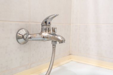 Pahalı tavan arası banyosunda musluk ve musluk var. Duş eklentisi olan bir köşedeki duş kabininin ayrıntıları