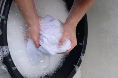 Beyaz arka plan üzerinde izole sabunlu suyla el giysiler bir kadın yıkar