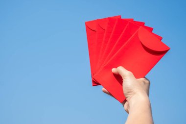 Mutlu Çin yeni yılı, el holding kırmızı zarf veya gökyüzü arka plan üzerinde denilen Angpao.
