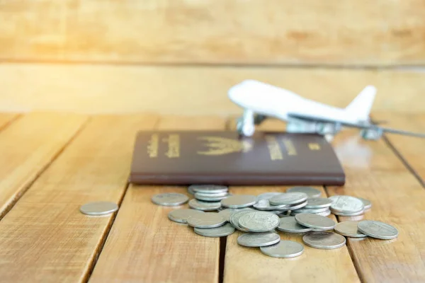 Money saving concept for vacation with coins stack, passport, and aircraft toy on the wooden backgrounds