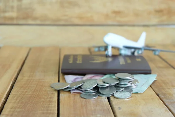 Money saving concept for vacation with coins stack, passport, and aircraft toy on the wooden backgrounds