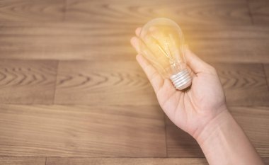 yeni fikir kavramı, ampul ahşap arka plan üzerinde yeni bilgi ile tutan genç kadın el