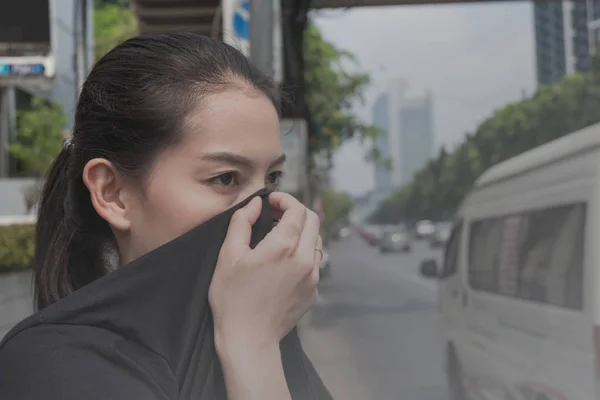 女性は悪い交通公害のため手で自分の鼻を閉じます ストックフォト