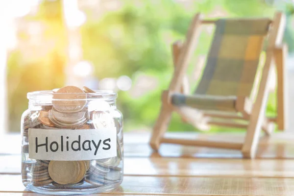 Ferienbudget-Konzept. Feriengeld-Sparkonzept. Geld im Geldbeutel für die Feiertage sammeln. Geldkrug mit Münzen und Strandsitz auf hölzernem Hintergrund — Stockfoto