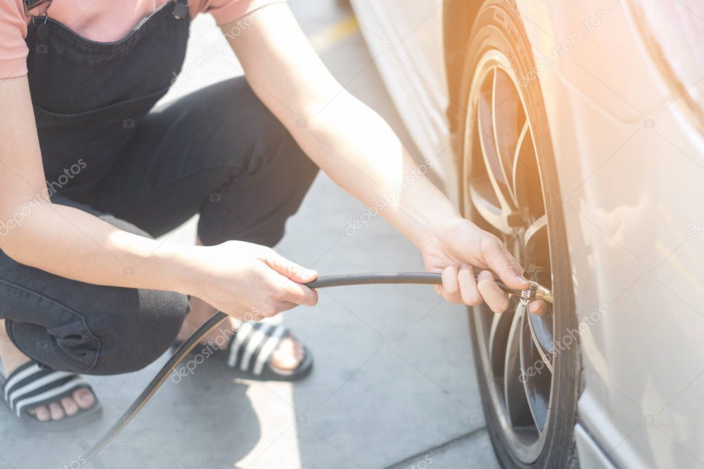 Asian woman filling air into a car tire to increase pressure car tire