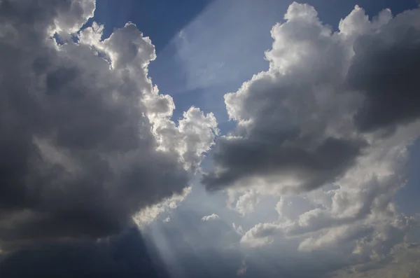 the sun makes its way through the clouds against the blue sky