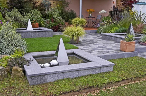 Containers of Carex grass and water features in a patio in a contemporary garden design