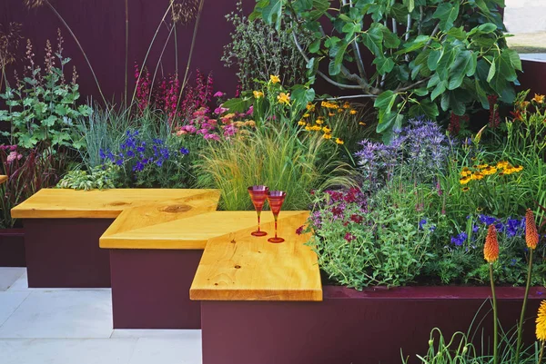 Colourful planting in \'Summer Cocktail\' and seating in a modern garden