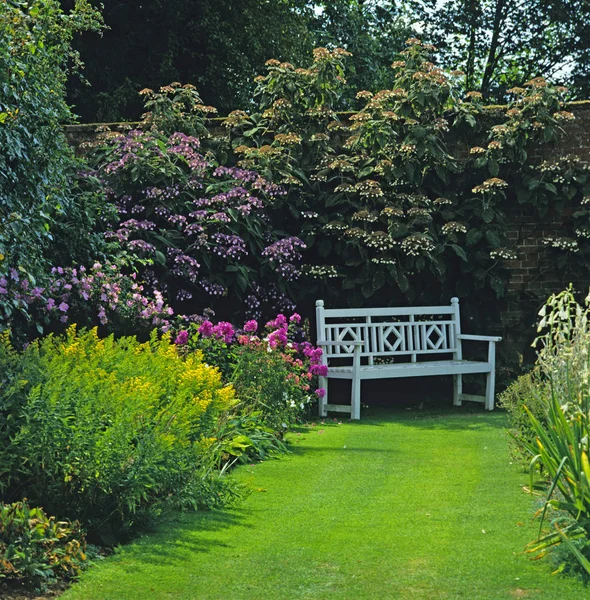 カラフルな花のボーダーの壁に囲まれた庭でロマンチックな席 — ストック写真