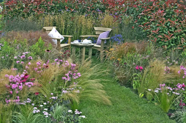 Corner of a cottage garden with outdoor eating and a display of — Stock Photo, Image