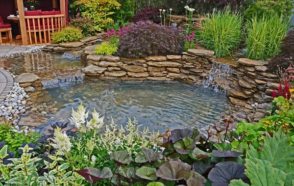 The pond area in an aquatic garden with planted rockery and wate — Stock Photo, Image