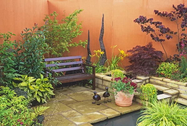 Сидіння поруч з водою в маленькому дворі саду — стокове фото