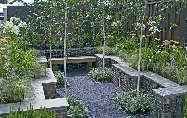 A small sunken courtyard garden with seating and mixed planting