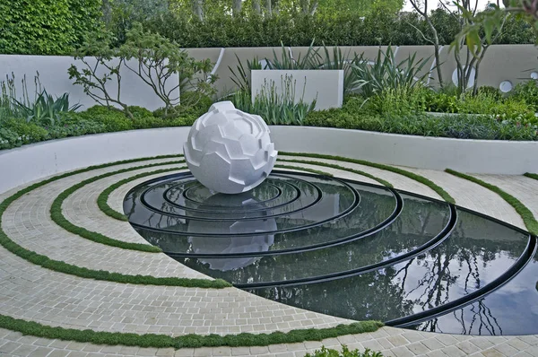 Jardin d'eau moderne avec sculpture et lits surélevés avec design circulaire — Photo