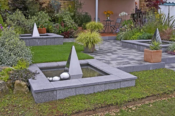 Conteneurs d'herbe Carex et les caractéristiques de l'eau dans un patio dans un jardin contemporain — Photo