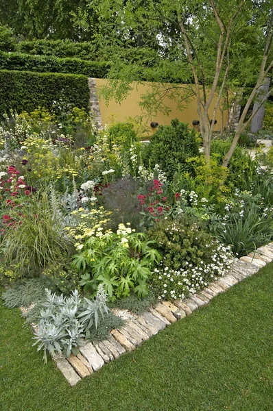 Ένας ενδιαφέρων Κήπος μεγάλης κλίμακας με αρχιτεκτονικά χαρακτηριστικά και ένα πολύχρωμο περίγραμμα λουλουδιών — Φωτογραφία Αρχείου