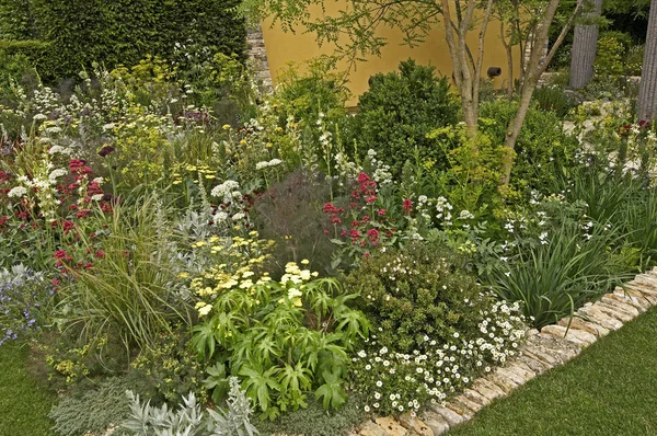 Ένας ενδιαφέρων Κήπος μεγάλης κλίμακας με αρχιτεκτονικά χαρακτηριστικά και ένα πολύχρωμο περίγραμμα λουλουδιών — Φωτογραφία Αρχείου