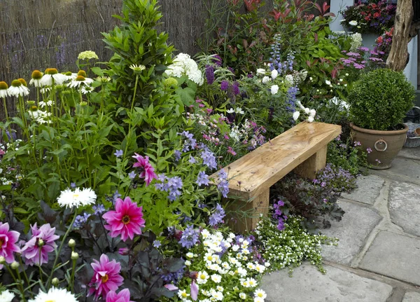 Renkli çiçekler ve oturma ile sakinleştirici ve dinlendirici bir alan creat için tasarlanmış geleneksel sazdan yazlık bahçe — Stok fotoğraf