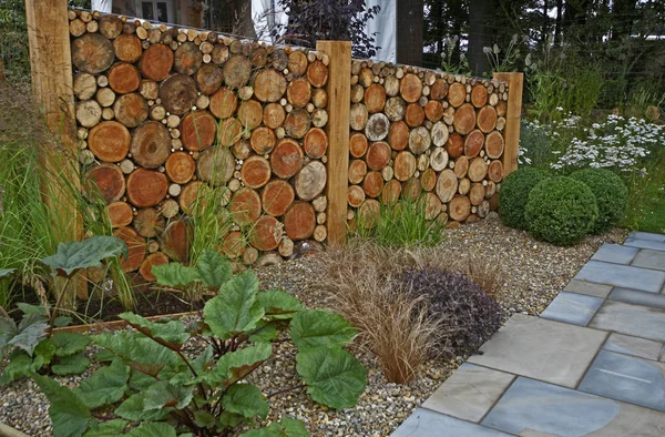Dekoracyjna ściana ogrodowa z pociętymi dziennikami i utwardzonym chodnikiem — Zdjęcie stockowe