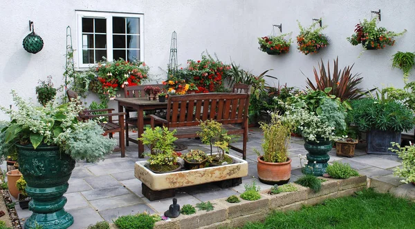 Un patio coloré avec des conteneurs plantés assortis et des paniers suspendus — Photo