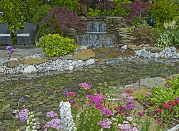 Водний сад з водоспадом у лісовій місцевості та квітковій обстановці — стокове фото