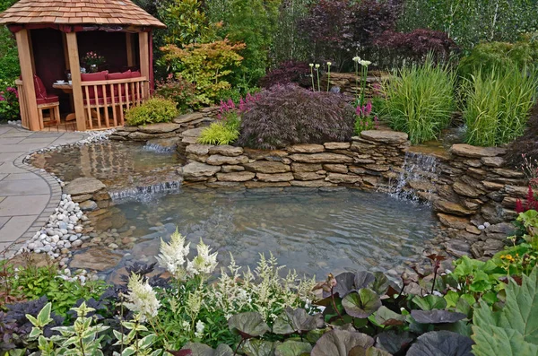 La zone étang et terrasse avec maison d'été dans un jardin aquatique — Photo