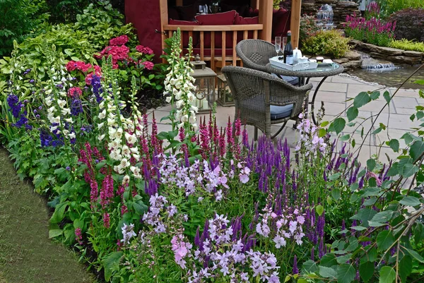 Le patio avec des sièges dans un jardin aquatique avec bordure florale colorée — Photo