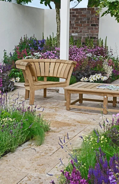 Egy modern kerti teraszos terület és elegáns fából készült bútorokkal, színes virágos határok körül — Stock Fotó