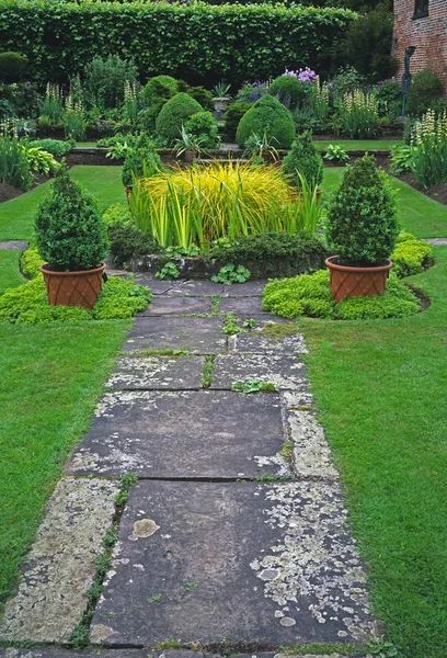 Jardim afundado com piscina central e seleção de gramíneas e topflowering hostas e datlillies no verão — Fotografia de Stock