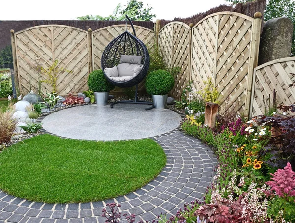 Un jardín urbano basado en curvas que fluyen alrededor de un patio y asiento colgante —  Fotos de Stock