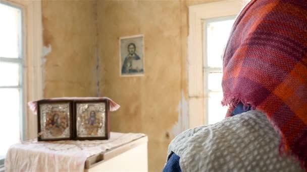Літня жінка молиться перед іконою. Крупним планом ззаду — стокове відео