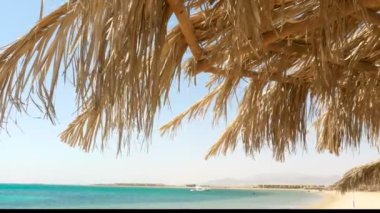 Hasır bir şemsiye ile deniz manzarası. 4k