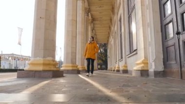 Kız turistik bir bina sütunlarla inceliyor. Ağır çekim