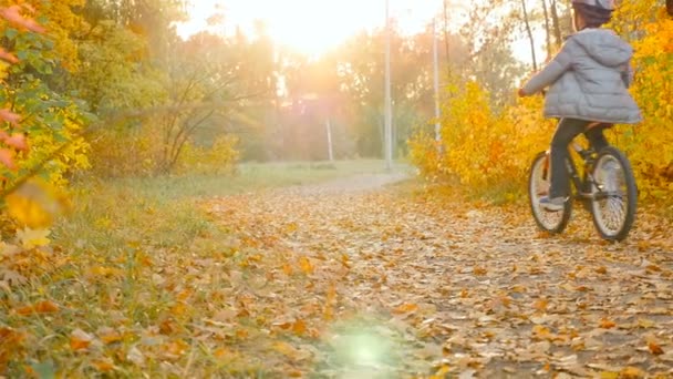 Un père avec deux enfants à vélo à travers la forêt d'automne. Beau paysage avec des arbres jaunes. Lumineux soleil éclat dans la lentille. Ukraine, Kiev. Parc "Amitié des peuples", 10.10.2018 — Video
