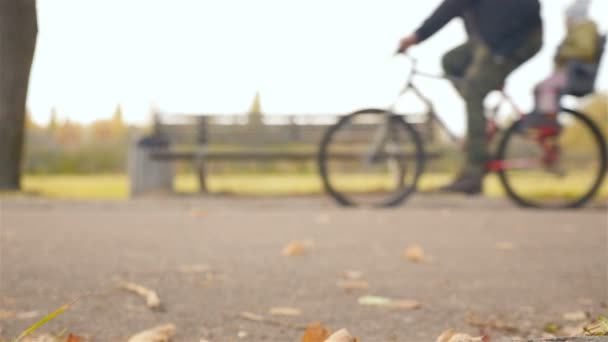 Um homem carrega uma criança numa bicicleta. Movimento lento — Vídeo de Stock