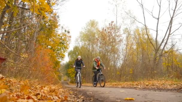 Ukrayna, Kiev. Park Fuar 10.27.18 Bisiklete binmek bir kızla genç adam. Ağır çekim. Güzel sonbahar park — Stok video