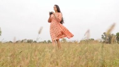 Sallama elbiseli güzel kız. Doğa fotoğrafçılığı. Ağır çekim. Elinde kamera