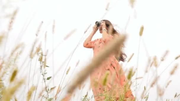 A menina com uma câmera fotografa a natureza. Linda morena. Movimento lento — Vídeo de Stock